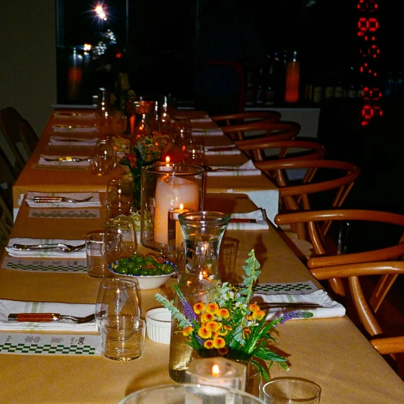 A candlelit dining table set with flowers, glassware, and Primo menus